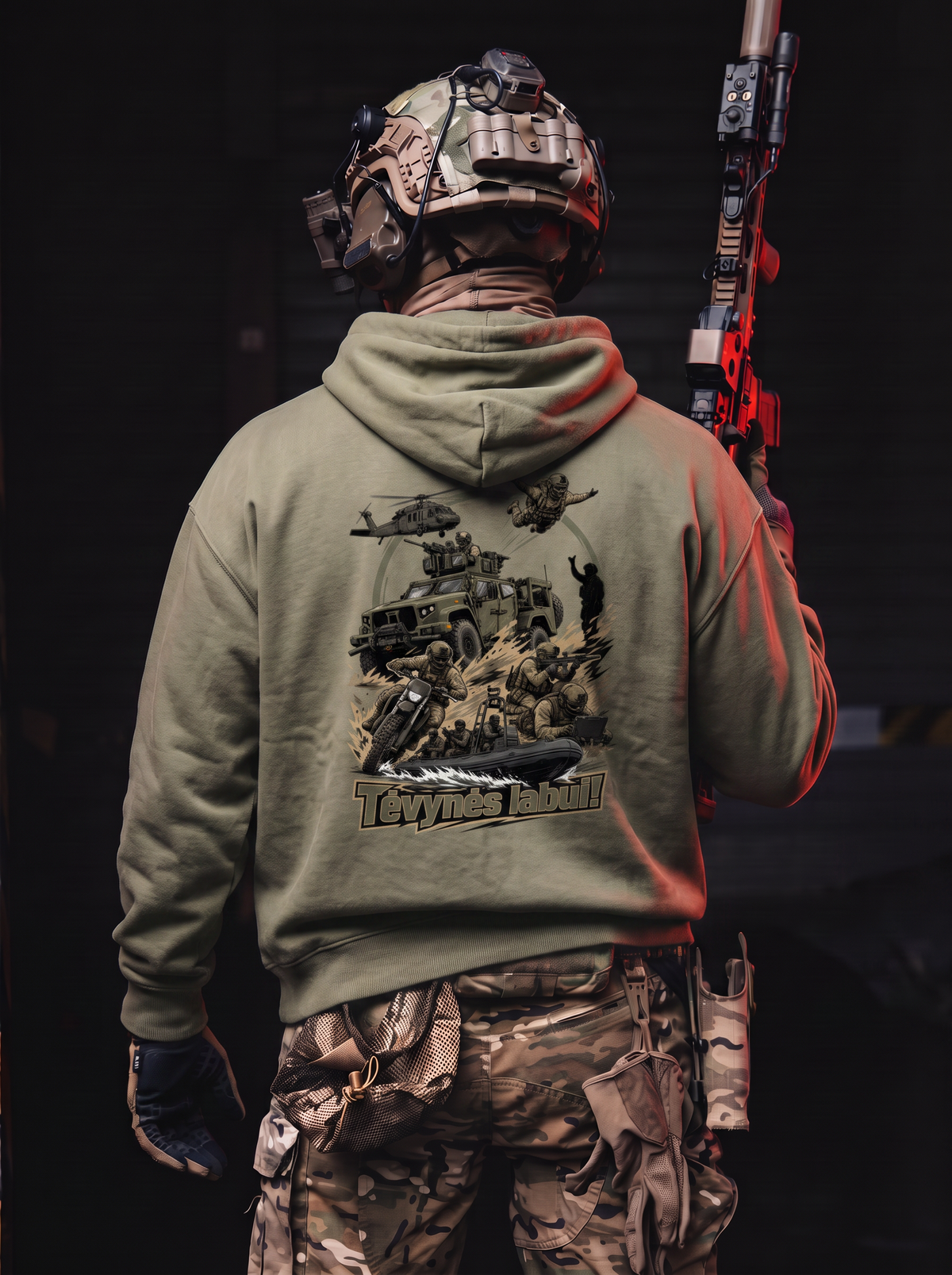 A person wearing tactical gear, including a camouflage helmet, vest, and cargo pants, is shown from behind wearing an olive green hoodie with a large military-themed graphic print on the back. The person is holding a rifle in a dark, moody setting.
