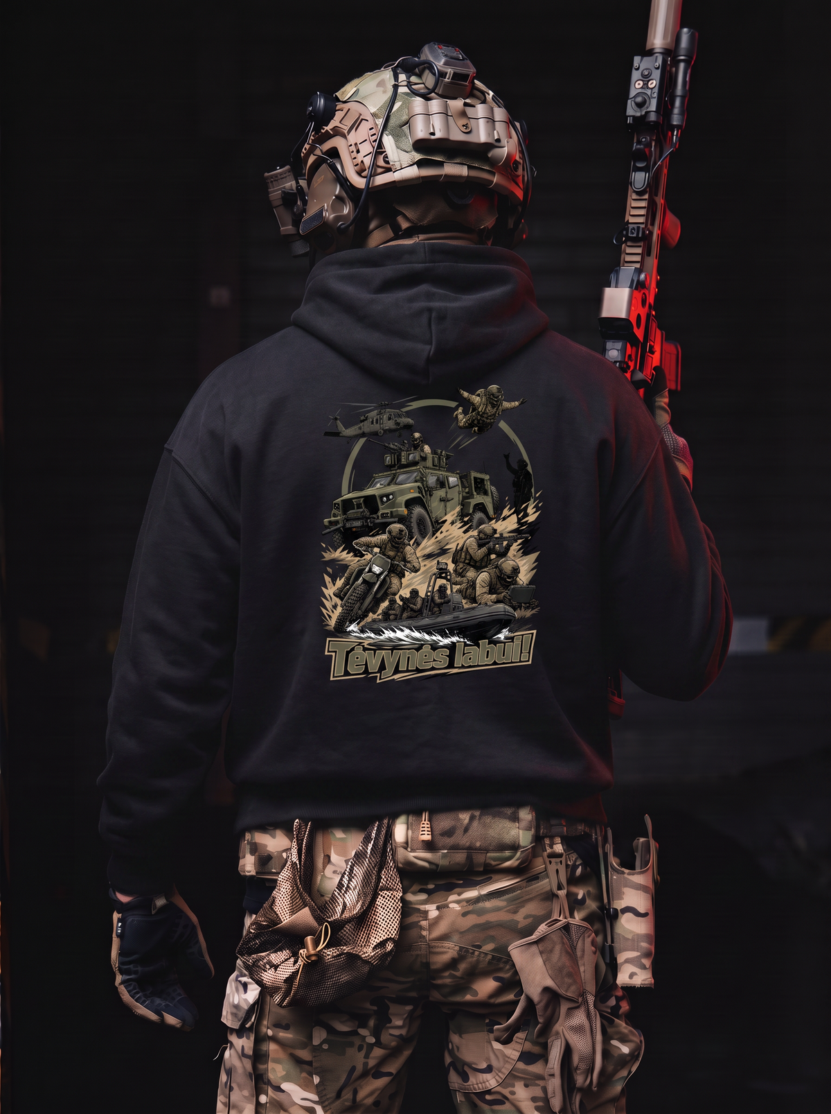 A person shown from behind wearing a black hoodie with a large tactical graphic print on the back, paired with camouflage cargo pants and a tactical helmet, holding a red and black rifle against a dark background.