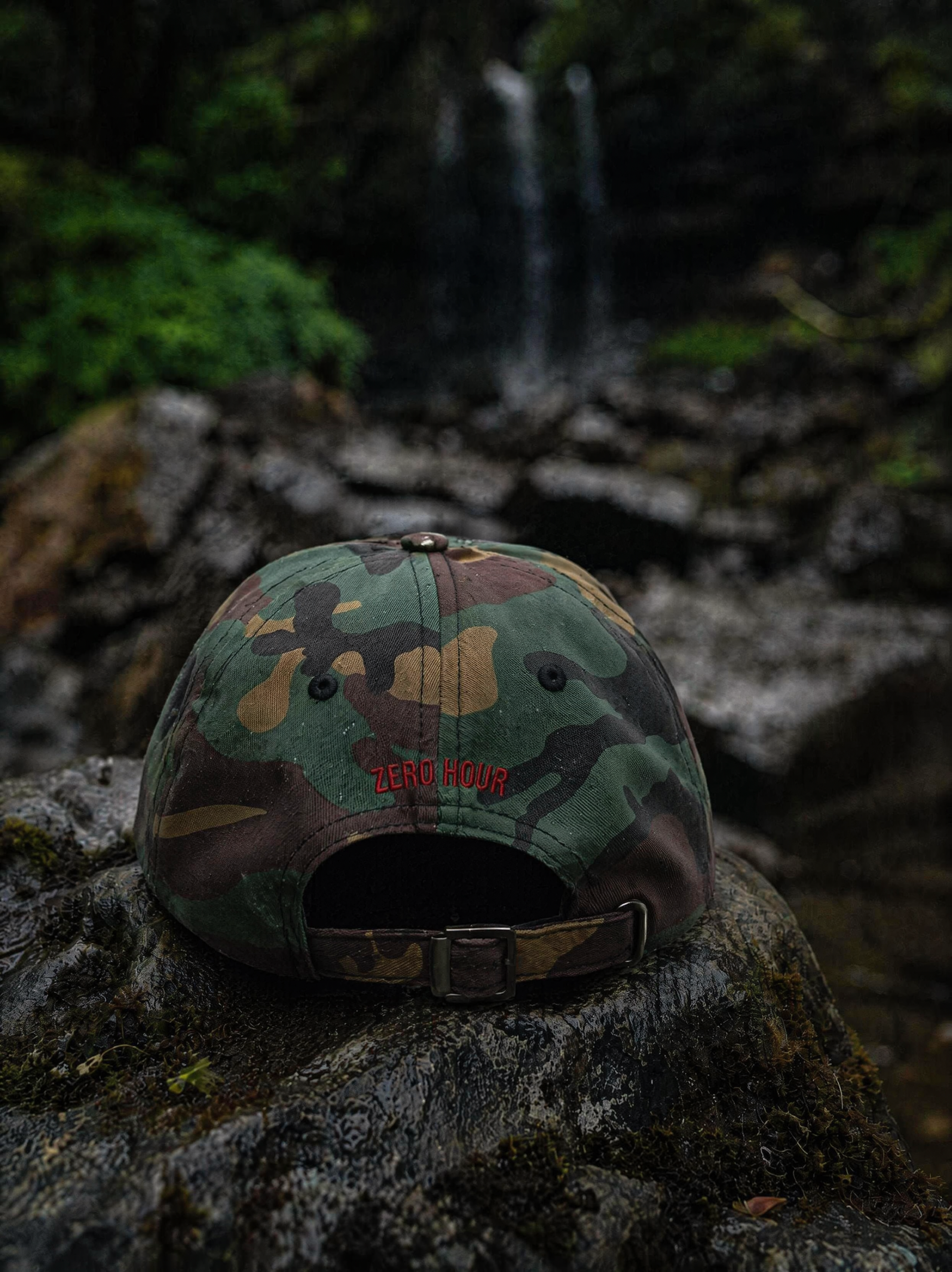 Camouflage cap with a brand logo on a rock in a forest setting