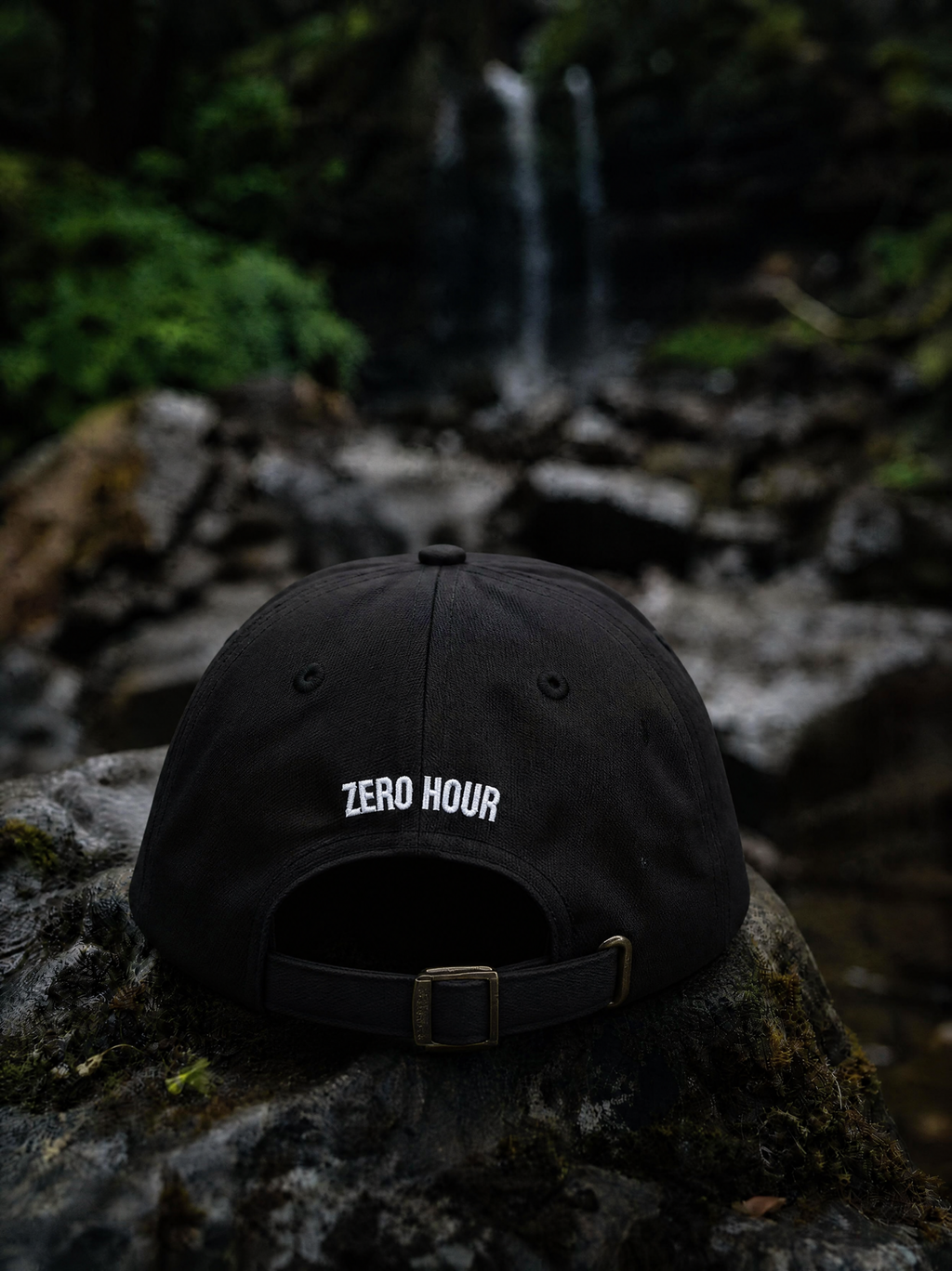 Black cap with 'ZERO HOUR' logo on a rock with a forest background