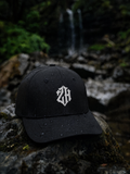 Black cap with a white logo on a stone surface with a natural background