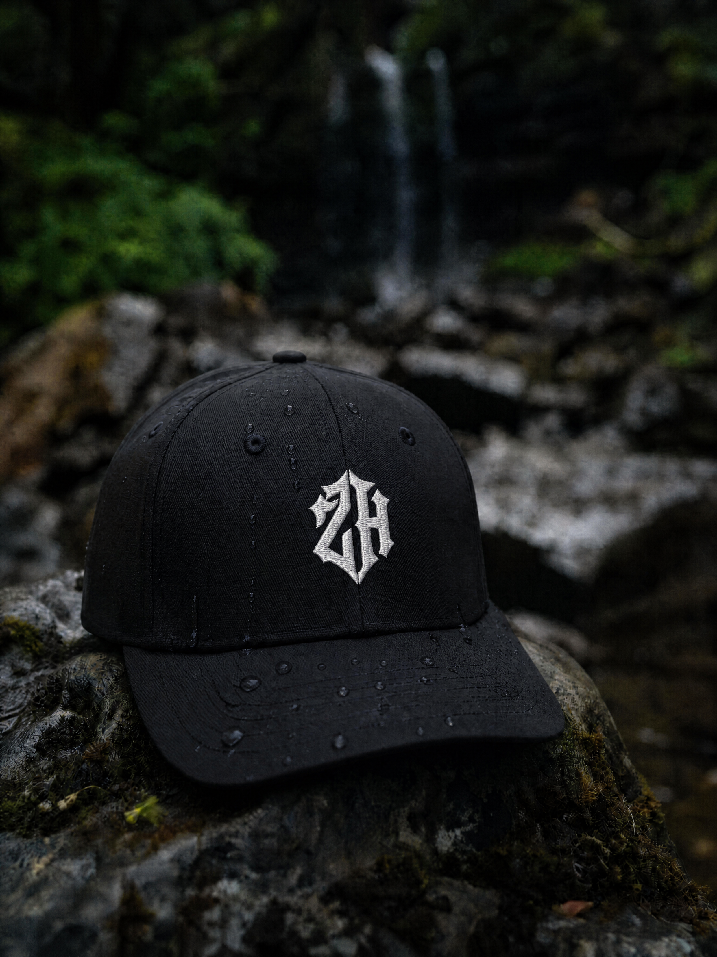 Black cap with a white logo on a stone surface with a natural background