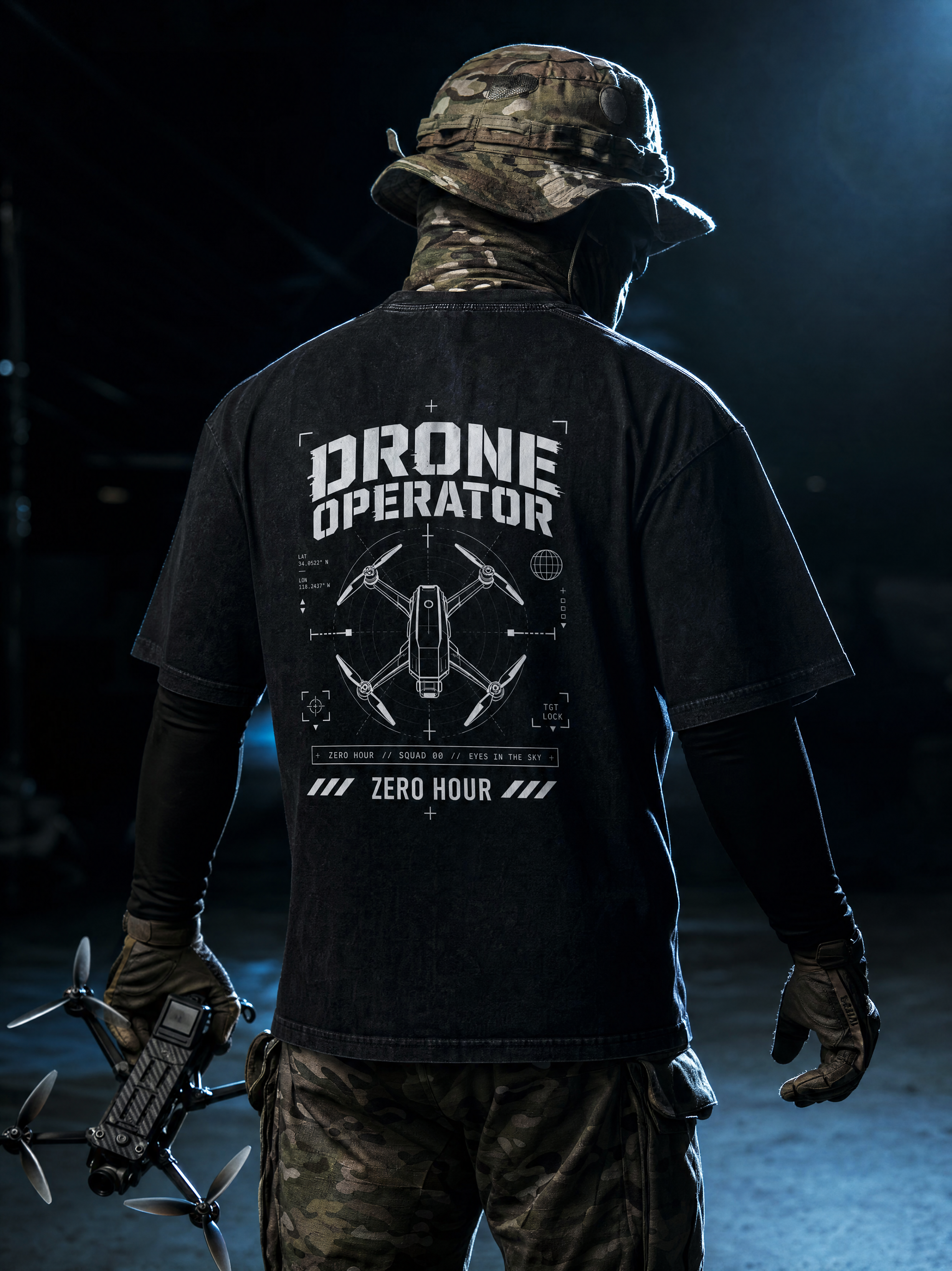 Person wearing a black 'Drone Operator' t-shirt with a drone design, holding a drone.