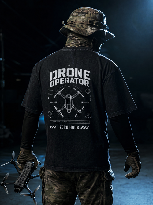 Person wearing a black 'Drone Operator' t-shirt with a drone design, holding a drone.