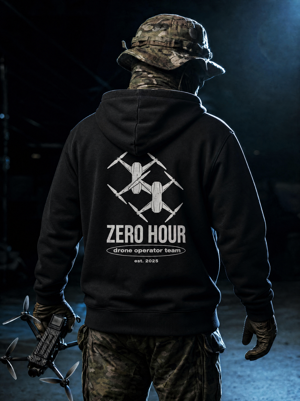Person wearing a black hoodie with 'Zero Hour drone operator team' logo, holding a drone.