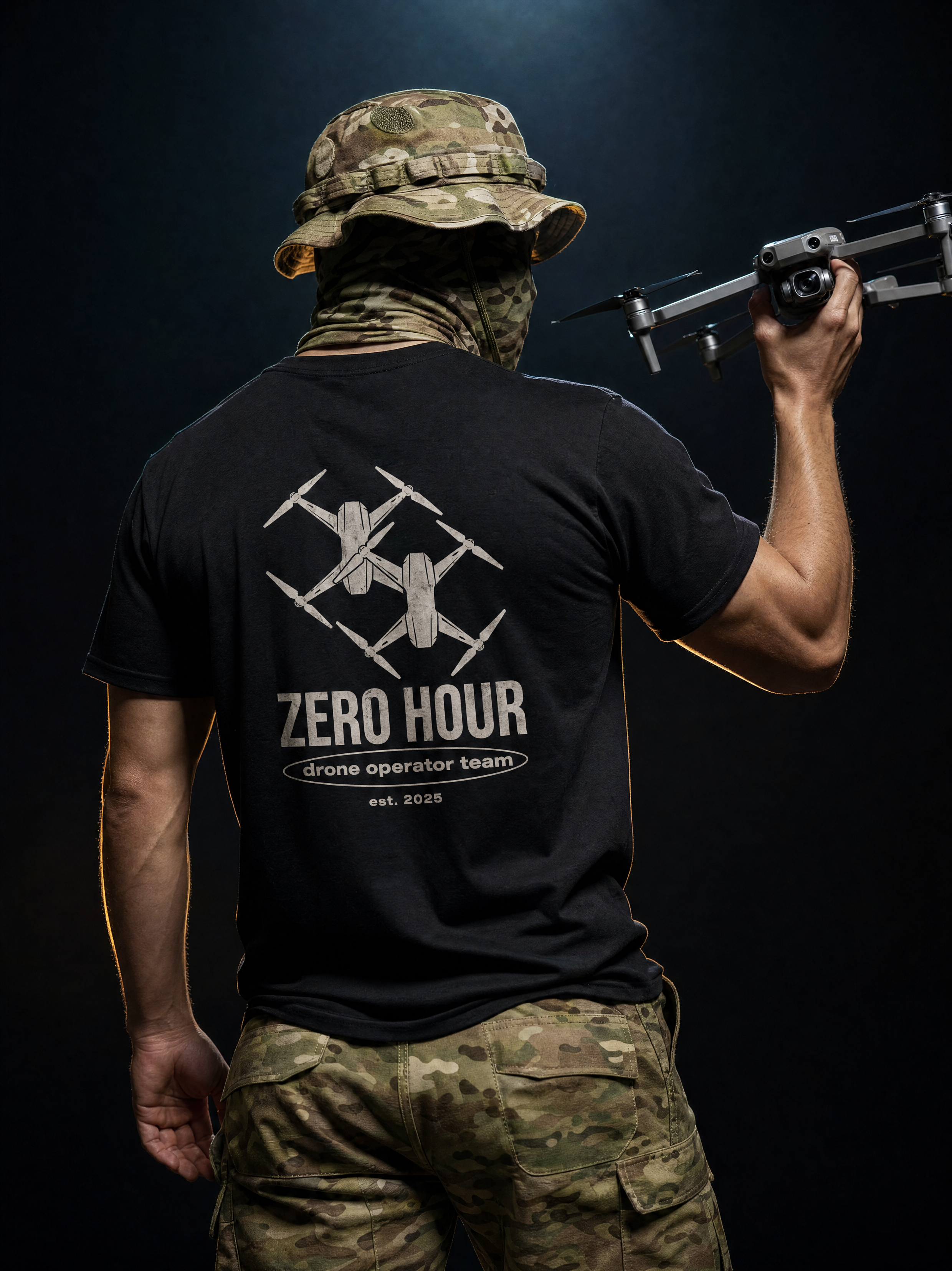 Person in camouflage gear holding a drone with 'Zero Hour' t-shirt visible