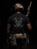Person wearing a black t-shirt with a skull design, holding a rifle, on a dark background