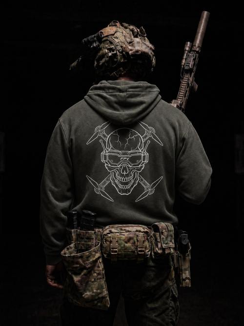 Person wearing a hoodie with a skull design and holding a rifle on a black background