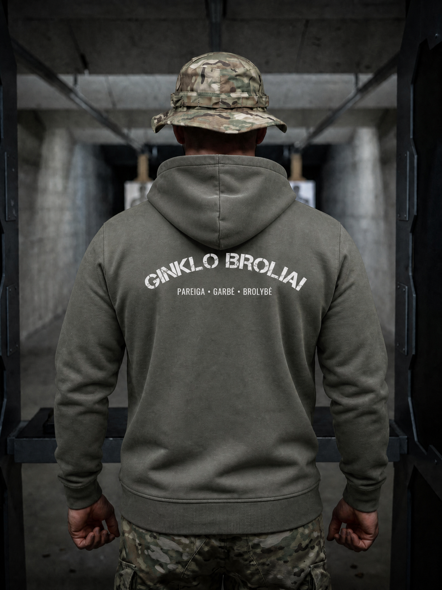 Person wearing a green hoodie with text on the back, standing in an indoor setting.
