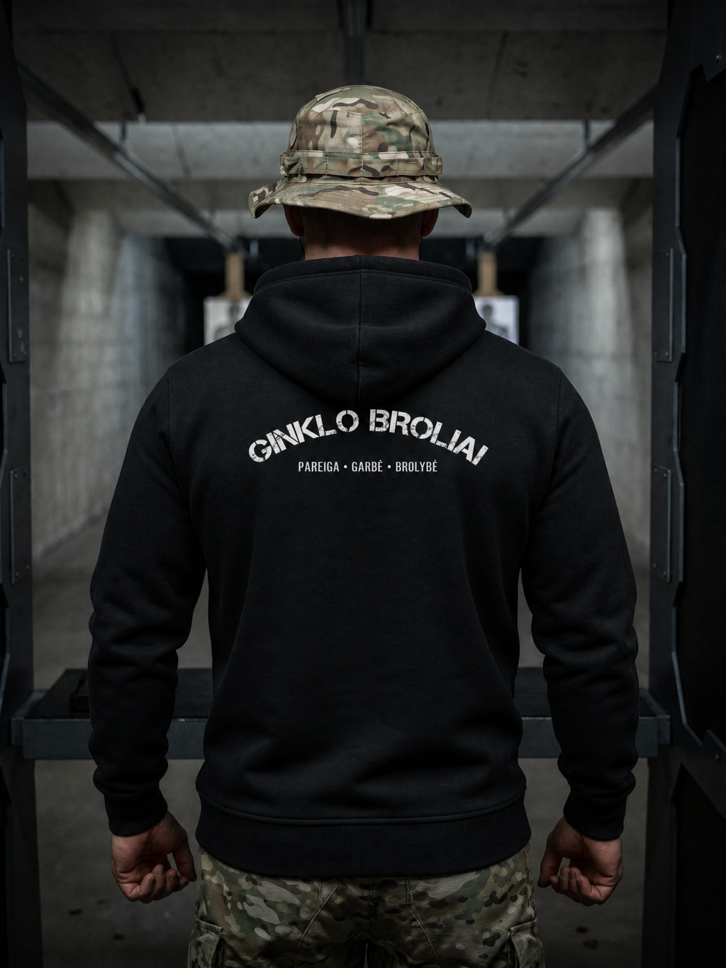 Person wearing a black hoodie with text on the back, standing in an indoor setting.