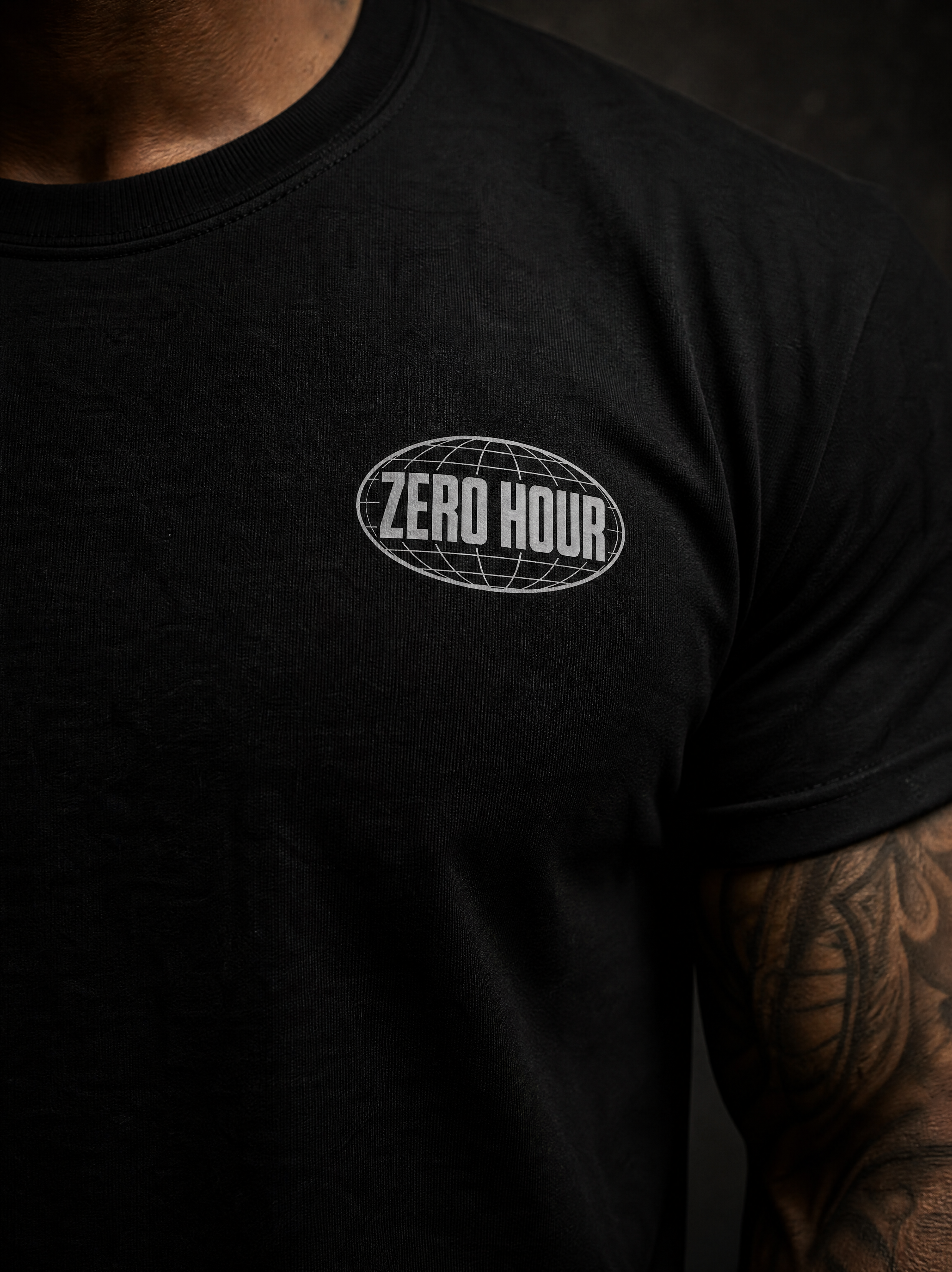 A close-up of a person wearing a black short-sleeve t-shirt with a white 'ZERO HOUR' oval globe graphic printed on the left chest.
