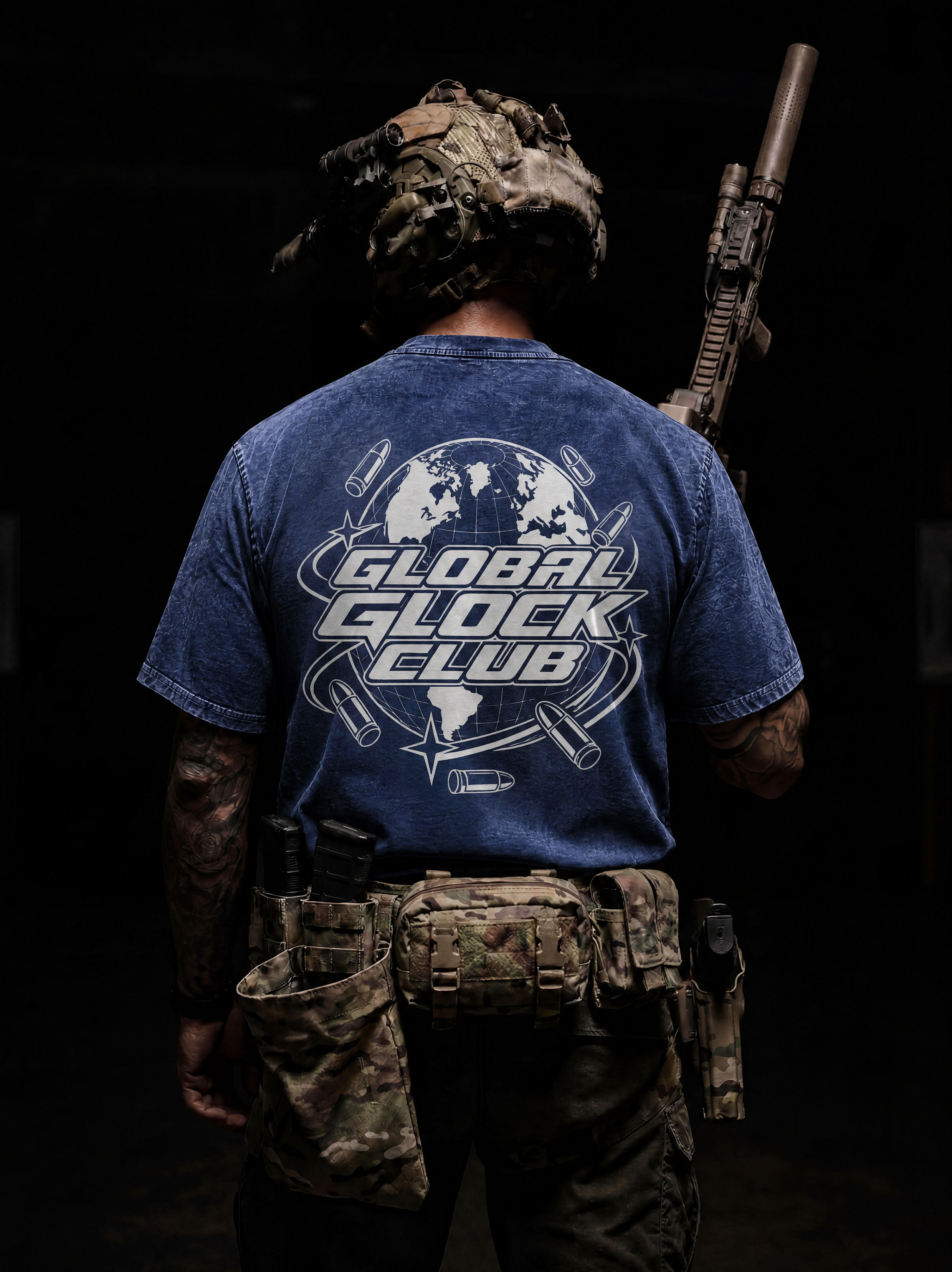 A person shown from behind wearing a blue graphic T-shirt with a large white and gray 'GLOBAL GLOCK CLUB' design on the back, along with tactical gear and a rifle over the shoulder in a dark setting.