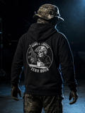 Person wearing a black hoodie with a graphic design on the back, standing in a dark setting.