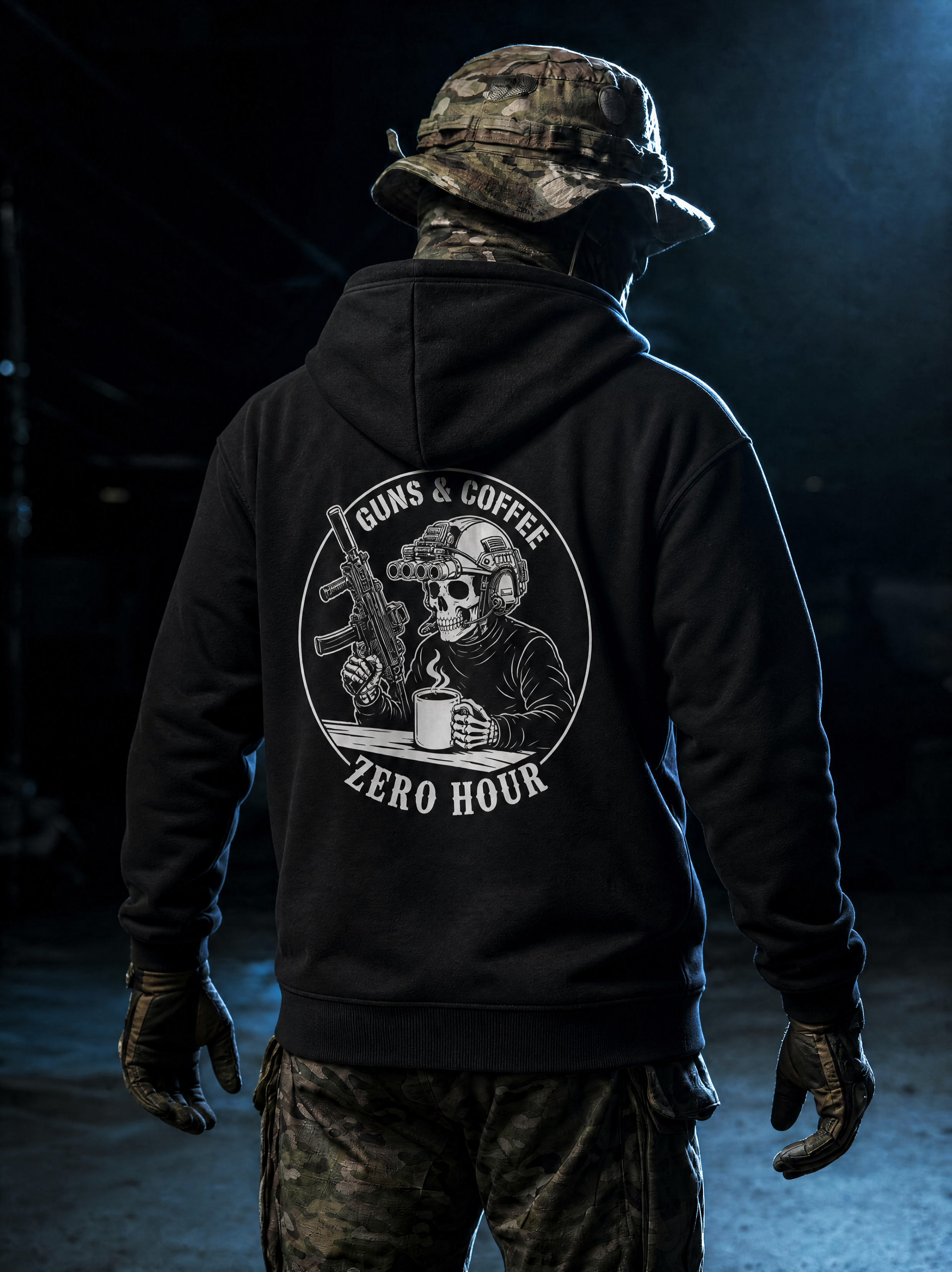 Person wearing a black hoodie with a graphic design on the back, standing in a dark setting.