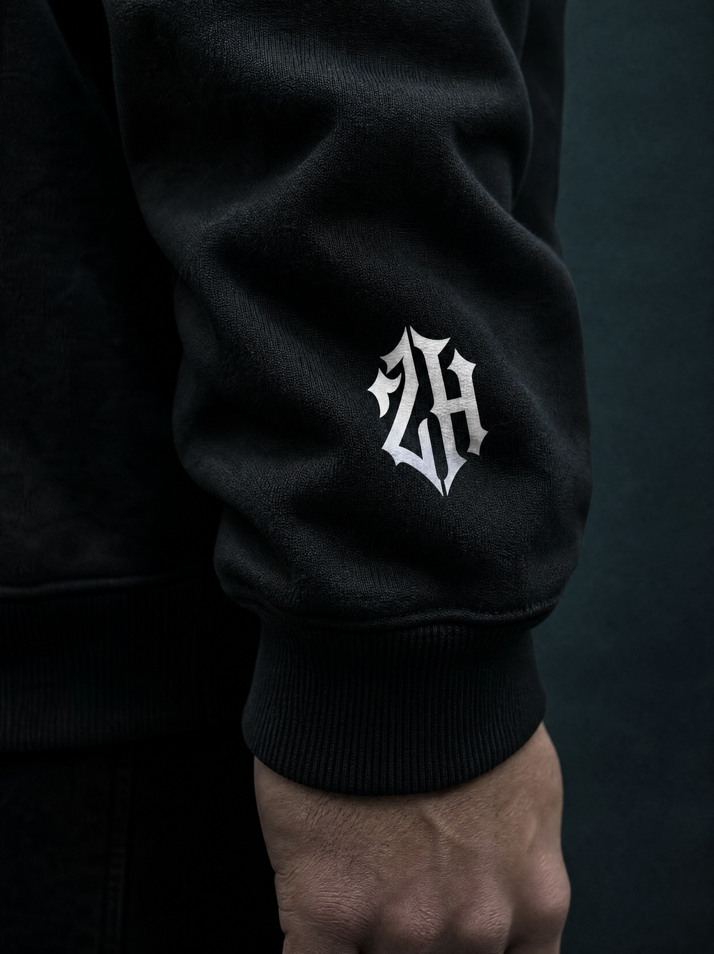 Black sweatshirt sleeve with a white logo on a dark background