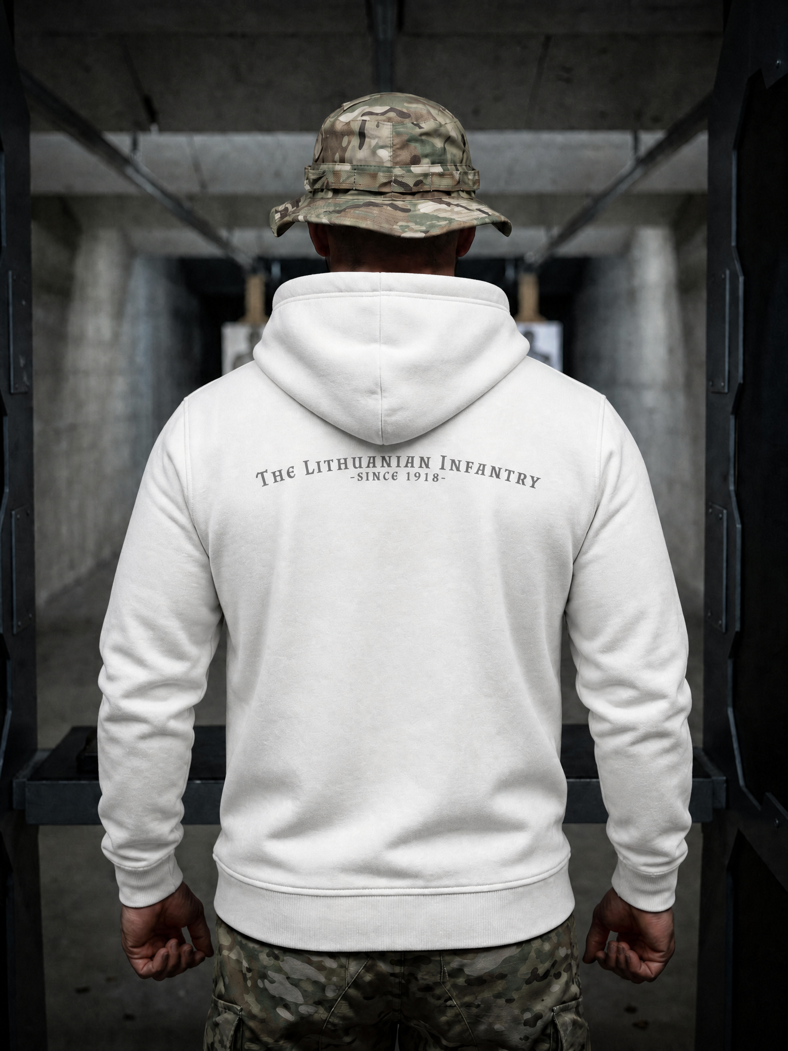 Person wearing a white hoodie with text and camouflage pants in an indoor setting