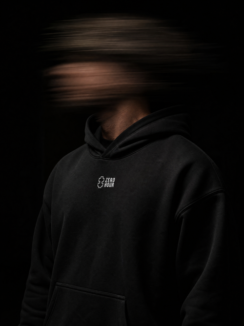 Person wearing a black hoodie with a Zero Hour logo on a dark background