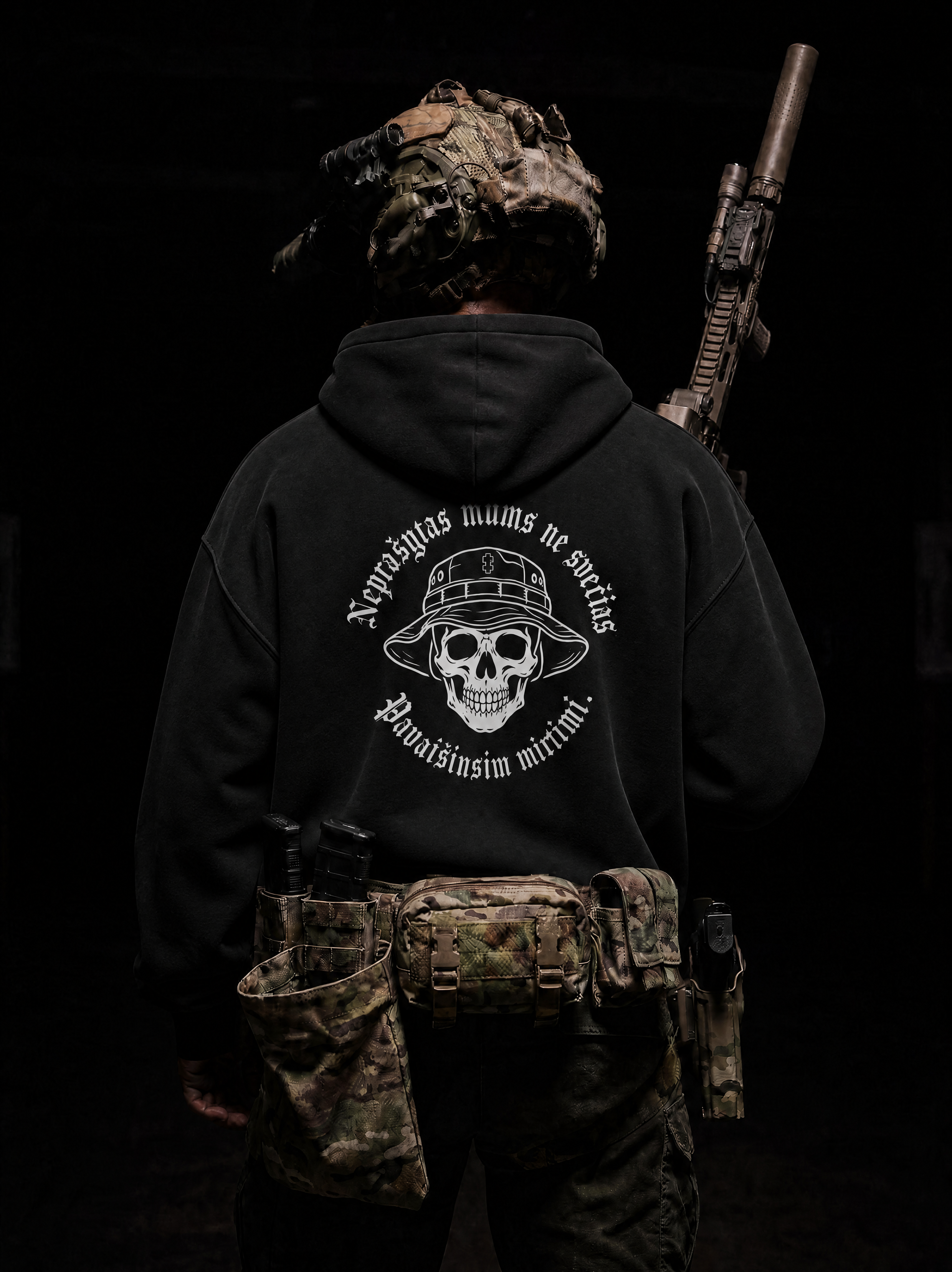 Person wearing a black hoodie with a skull design and text, holding a rifle on a dark background