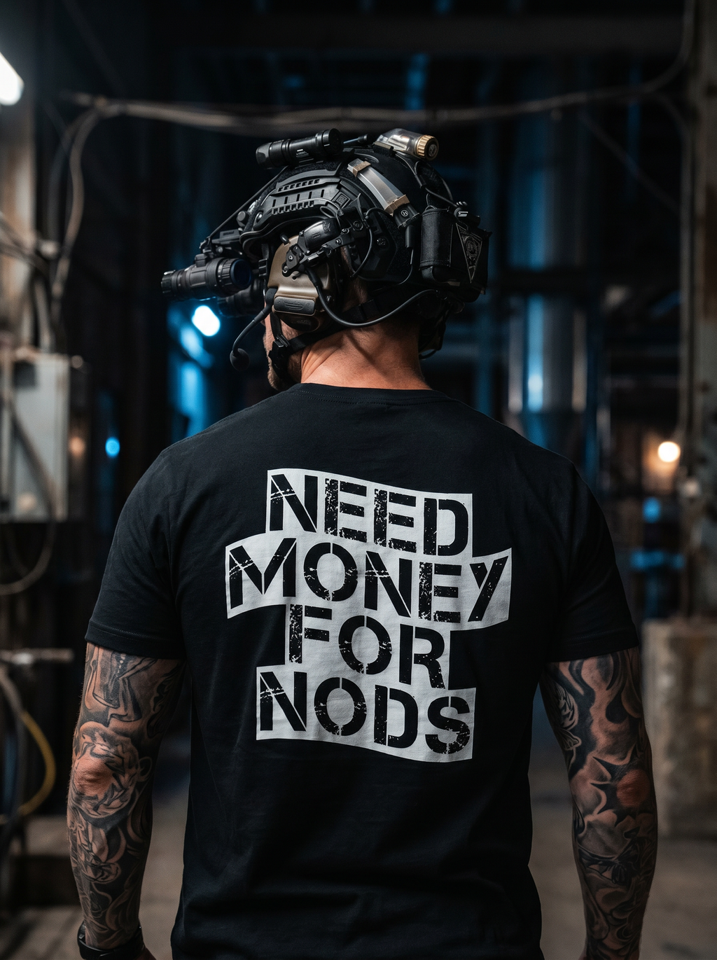 Person wearing a black t-shirt with 'NEED MONEY FOR NODS' text, standing in a dark industrial setting.