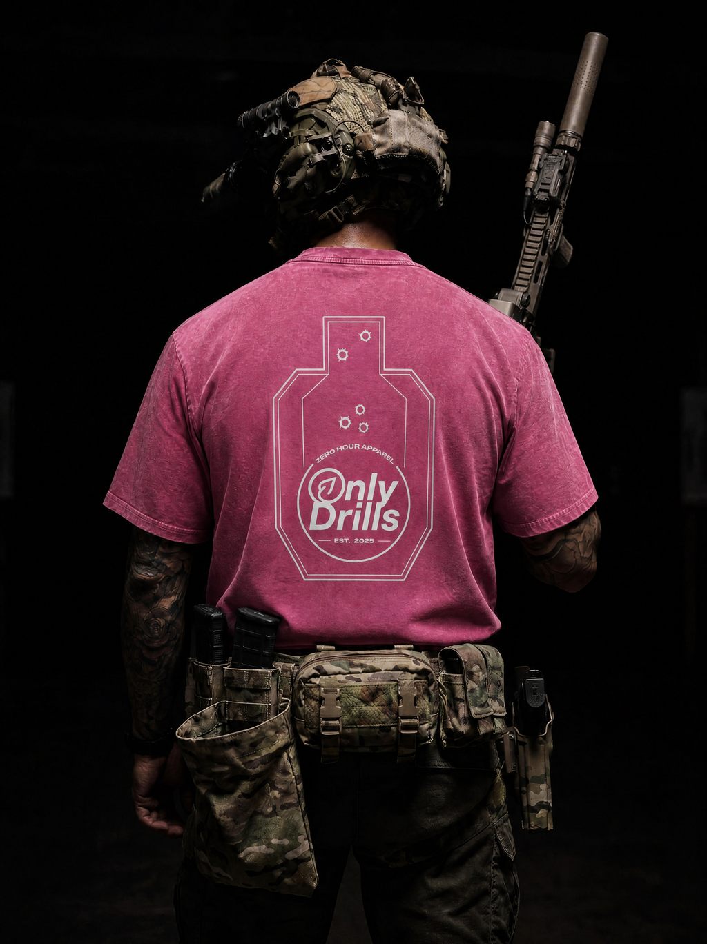 Person wearing a pink 'Only Drills' t-shirt with camouflage gear and a rifle on a black background