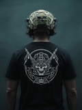 Person wearing a black t-shirt with a white graphic design on the back, against a dark background.