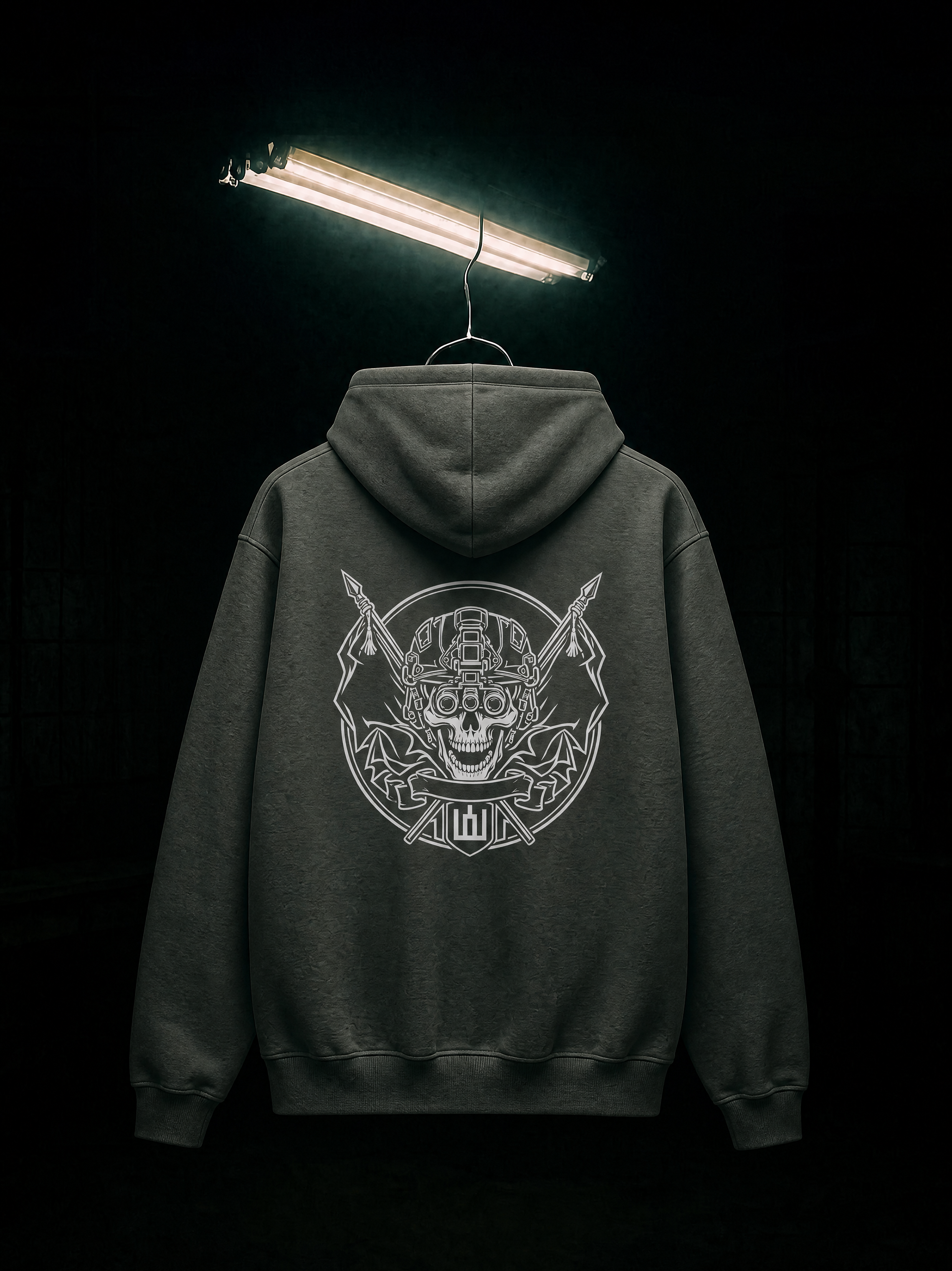 Dark hoodie with a skull and crossbones design on the back, illuminated by a single light source against a black background.