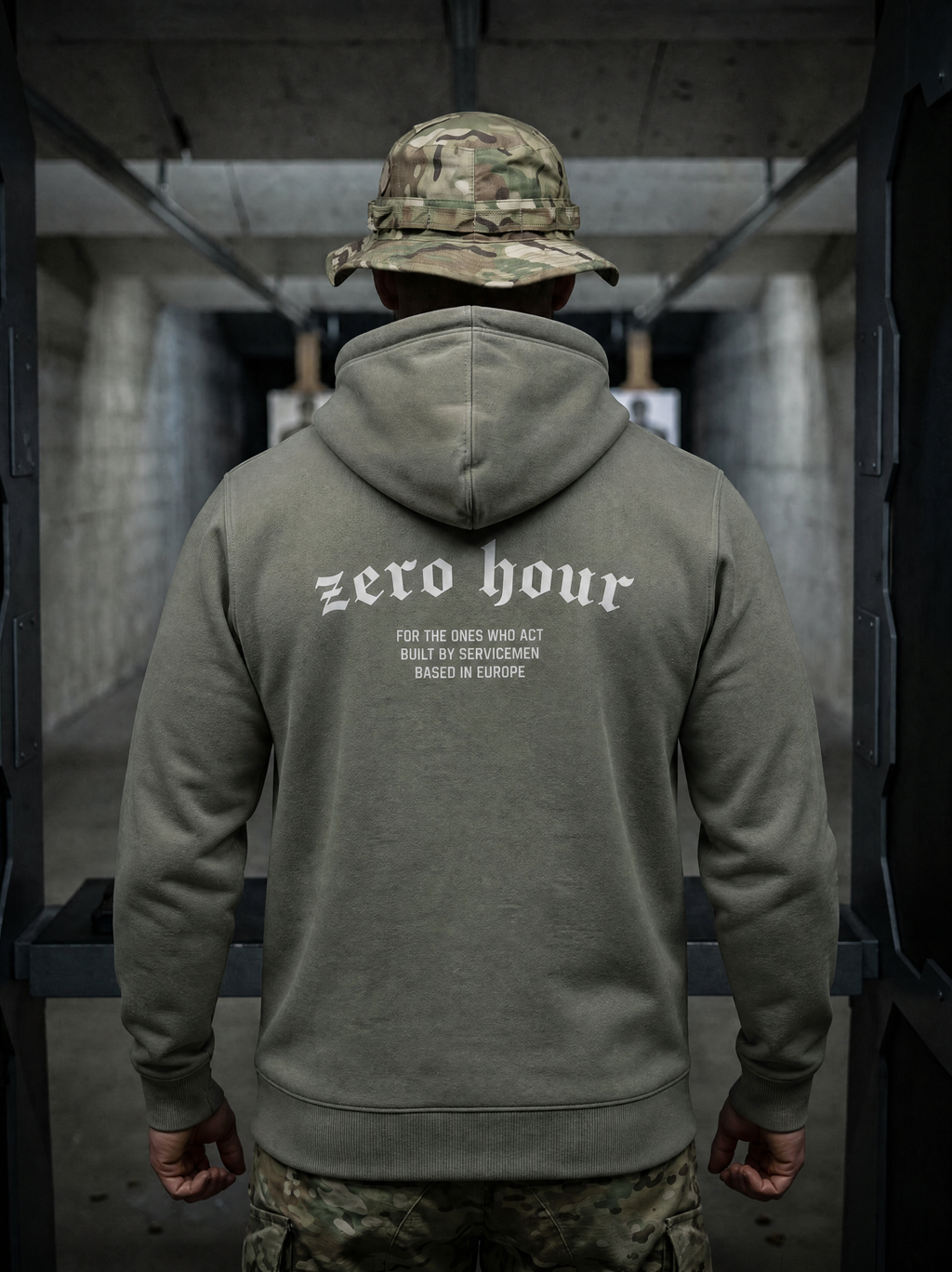 Person wearing a green hoodie with 'zero hour' text, standing in an industrial setting.