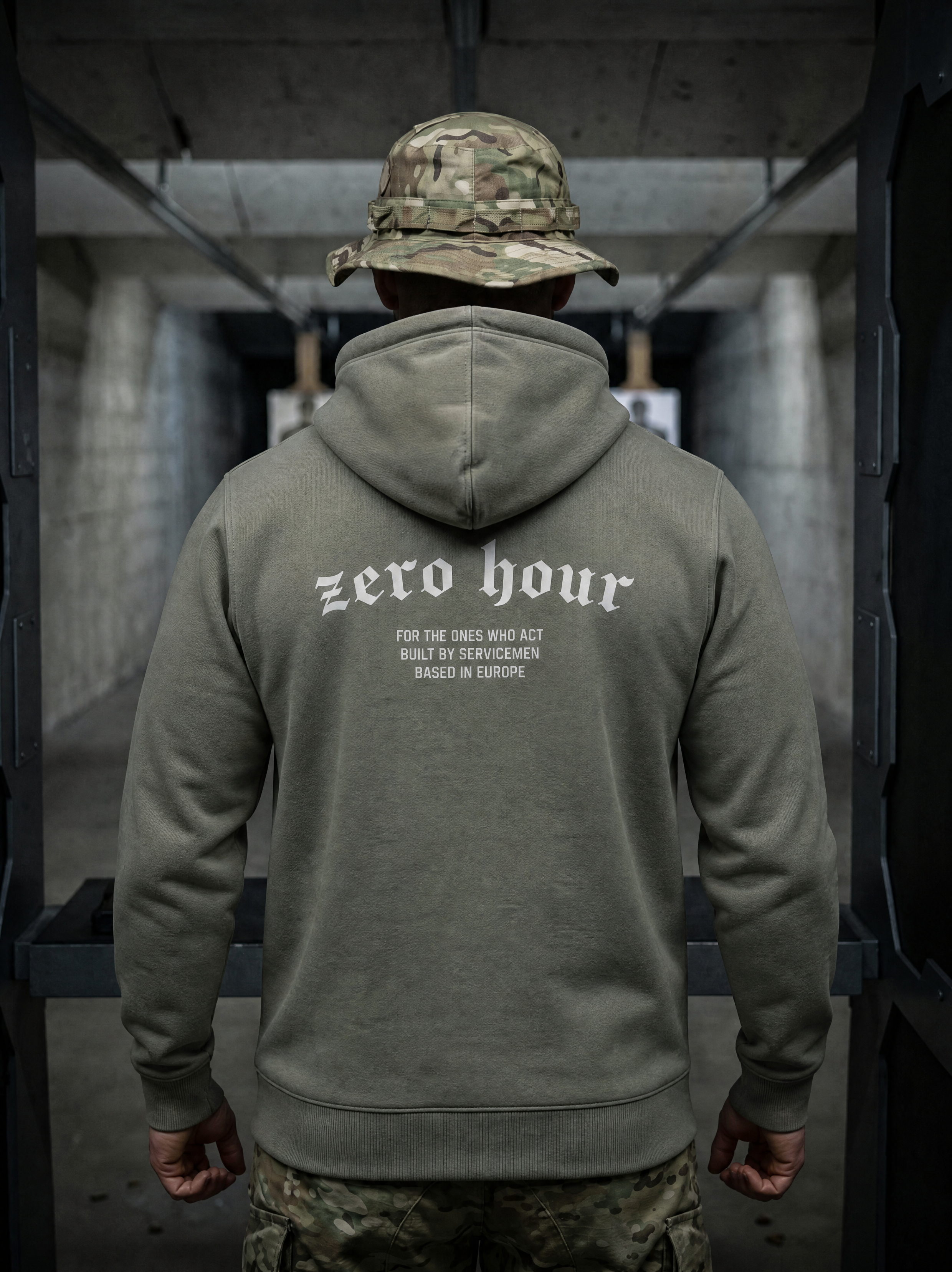 Person wearing a green hoodie with 'zero hour' text, standing in an industrial setting.