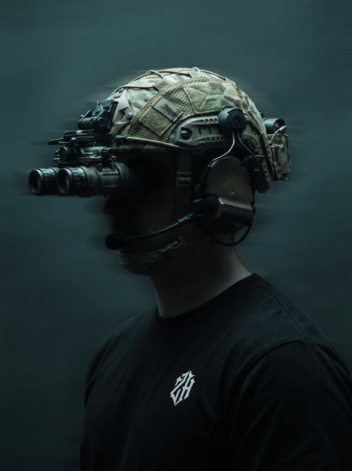 Person wearing a tactical helmet with night vision goggles on a dark background